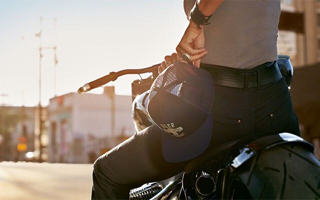 Na posnetku od blizu motoristka v rokah drži Boxer kapo iz kolekcije in nosi ženske jeans hlače RoadCrafted.